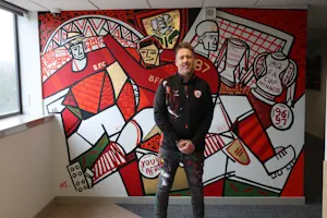 Ben in front of 1887 mural for news